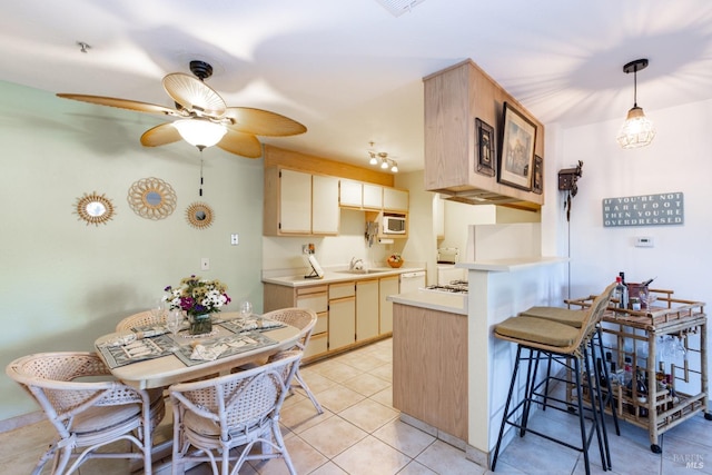 kitchen with kitchen peninsula, ceiling fan, sink, hanging light fixtures, and light tile patterned flooring