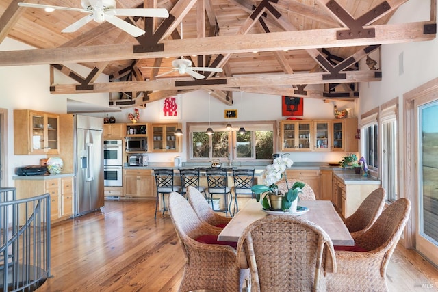 dining room featuring ceiling fan, light hardwood / wood-style floors, beam ceiling, and high vaulted ceiling