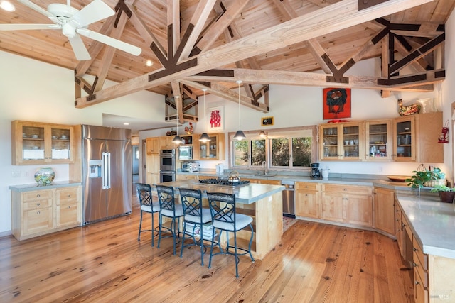 kitchen featuring appliances with stainless steel finishes, a center island, light hardwood / wood-style floors, and high vaulted ceiling