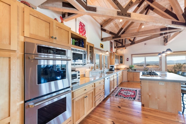 kitchen featuring beam ceiling, a center island, stainless steel appliances, and light brown cabinets