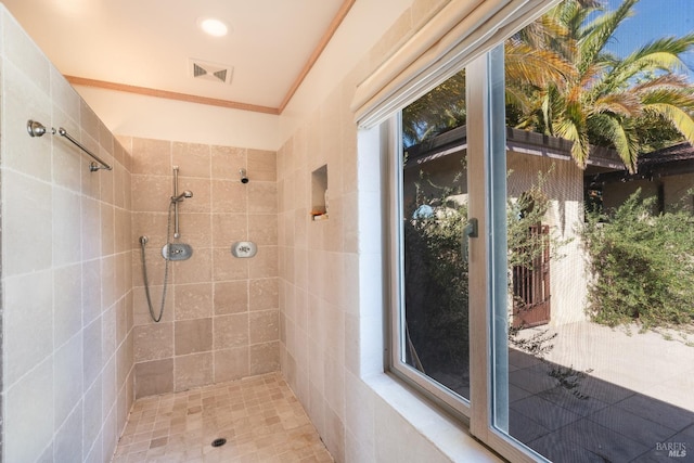 bathroom with a tile shower and ornamental molding