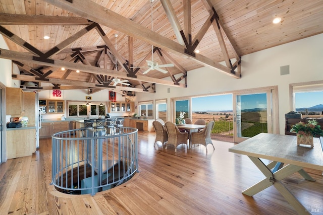 dining room featuring beam ceiling, light hardwood / wood-style flooring, high vaulted ceiling, and wood ceiling