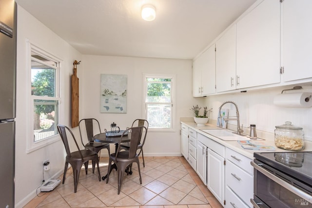 kitchen with sink, white cabinets, a healthy amount of sunlight, and light tile patterned floors