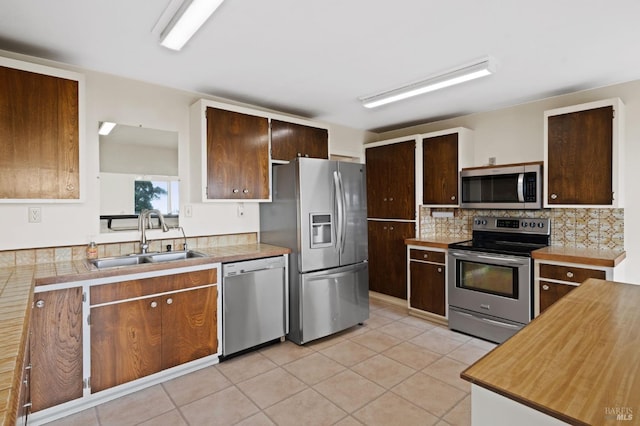 kitchen featuring backsplash, sink, appliances with stainless steel finishes, and light tile patterned flooring