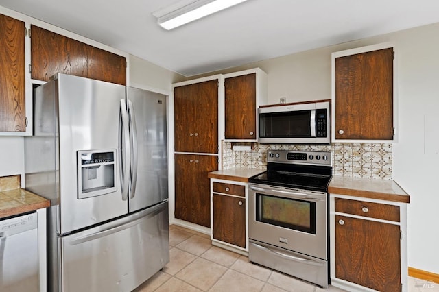 kitchen with light tile patterned flooring, appliances with stainless steel finishes, and decorative backsplash