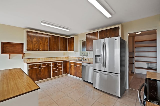 kitchen featuring appliances with stainless steel finishes, dark brown cabinets, light tile patterned floors, and sink