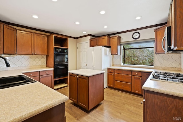 kitchen featuring light hardwood / wood-style flooring, stainless steel appliances, a kitchen island, sink, and decorative backsplash