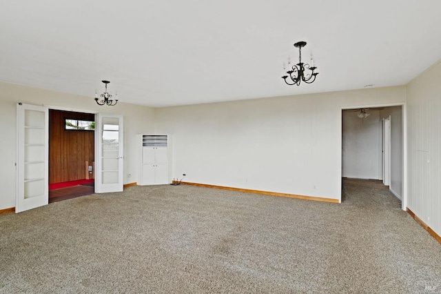 carpeted empty room featuring an inviting chandelier