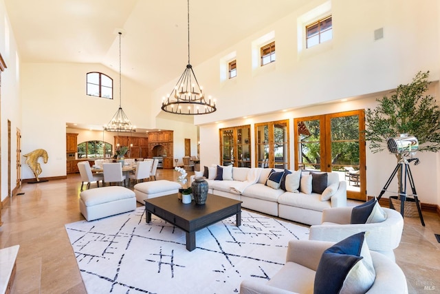 living room with high vaulted ceiling, an inviting chandelier, and french doors