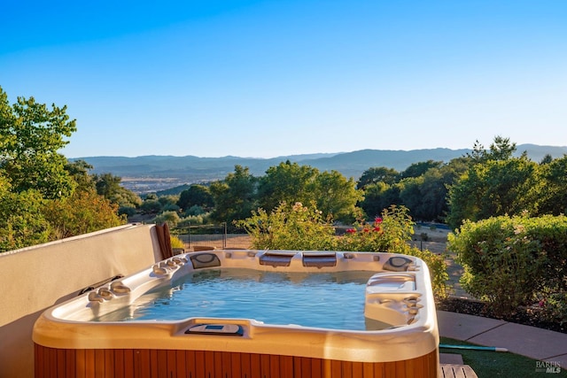 view of swimming pool with a mountain view and a hot tub