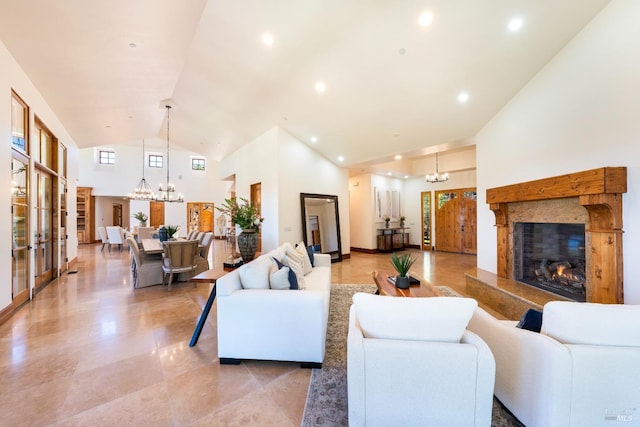 living room with an inviting chandelier, a high end fireplace, and high vaulted ceiling