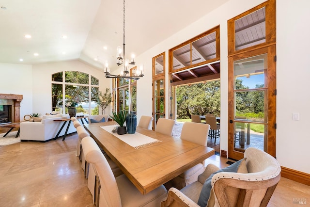 dining space featuring plenty of natural light, a chandelier, lofted ceiling, and a fireplace