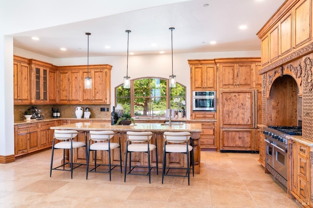 kitchen featuring tasteful backsplash, light stone counters, decorative light fixtures, a center island with sink, and high quality appliances