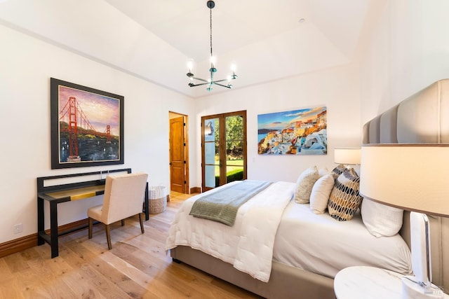 bedroom featuring a chandelier, light wood-type flooring, and french doors