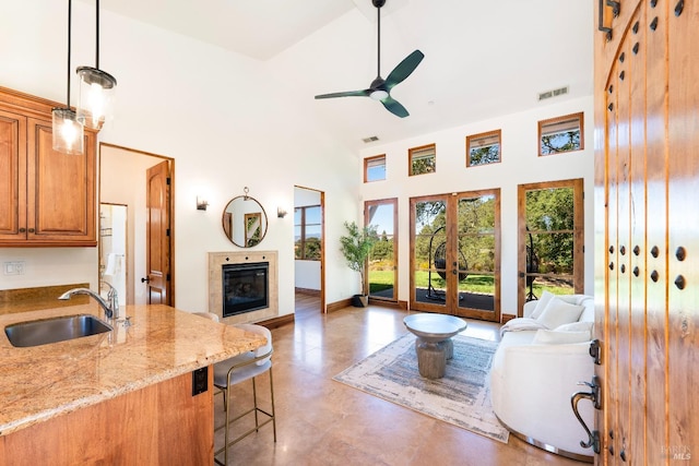 living room with french doors, a towering ceiling, ceiling fan, and sink