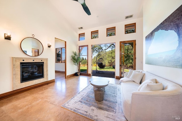 living room featuring a tile fireplace, ceiling fan, and high vaulted ceiling