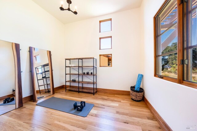 exercise area featuring a chandelier and light wood-type flooring