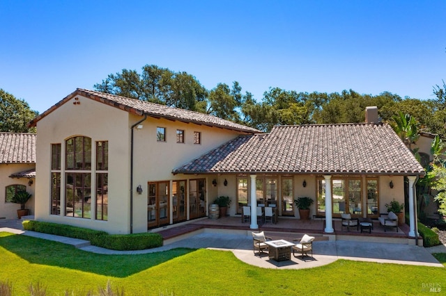 rear view of property featuring french doors, a yard, and a patio area