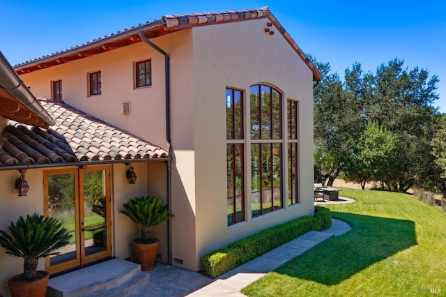 view of property exterior with a yard and french doors