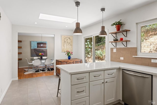 kitchen featuring light stone countertops, dishwasher, a skylight, plenty of natural light, and kitchen peninsula