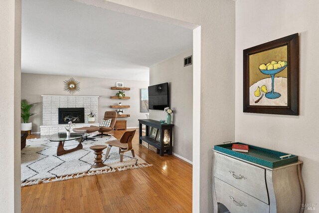 living room featuring a brick fireplace and wood-type flooring