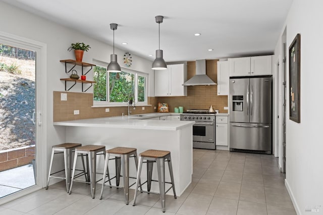 kitchen featuring white cabinetry, kitchen peninsula, stainless steel appliances, tasteful backsplash, and wall chimney exhaust hood