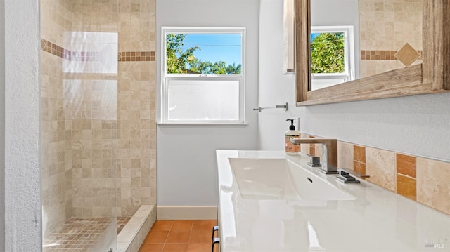 bathroom featuring tile patterned flooring, tiled shower, and vanity