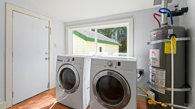 clothes washing area with light tile patterned floors, washer and dryer, and secured water heater