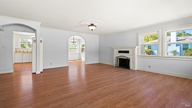 unfurnished living room with hardwood / wood-style floors, crown molding, and an inviting chandelier