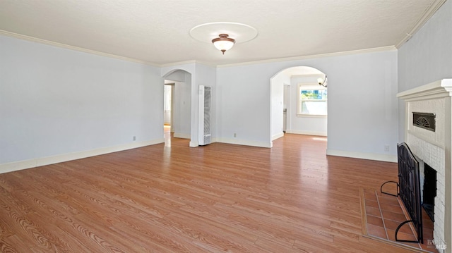 unfurnished living room with hardwood / wood-style flooring, a brick fireplace, and crown molding