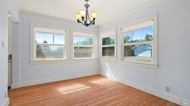 unfurnished room with light hardwood / wood-style floors, a wealth of natural light, crown molding, and a notable chandelier