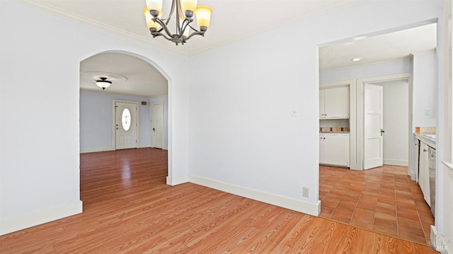 spare room with light hardwood / wood-style floors, crown molding, and a notable chandelier