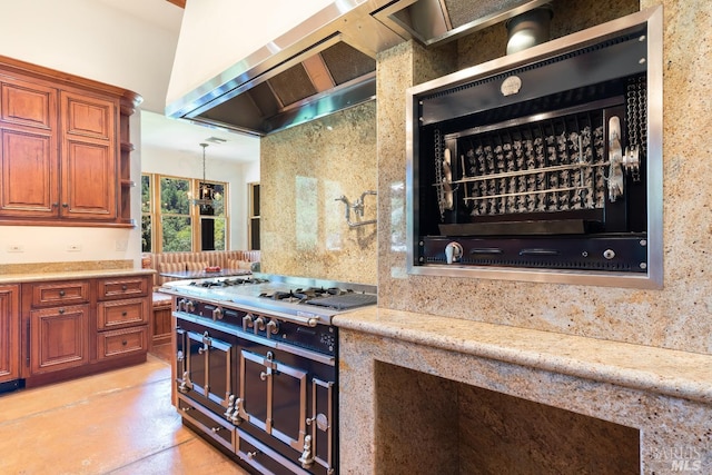 kitchen with stainless steel gas stovetop, wall chimney exhaust hood, and light stone counters