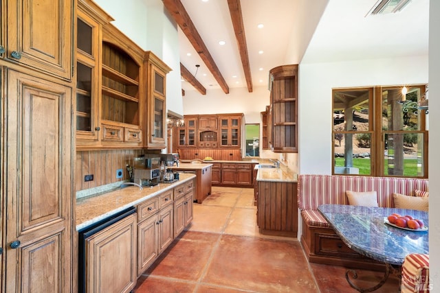 kitchen with a kitchen island, beam ceiling, light stone counters, light tile patterned floors, and sink