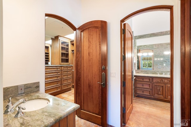 bathroom featuring tile patterned floors, decorative columns, decorative backsplash, and vanity