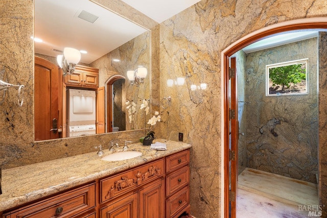 bathroom featuring stacked washer / drying machine and vanity