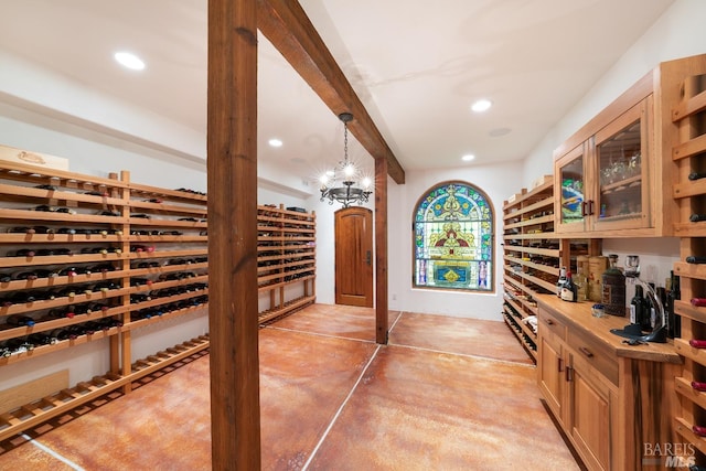 wine room with an inviting chandelier and beamed ceiling