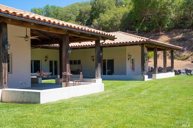 rear view of property with ceiling fan, a patio, and a yard