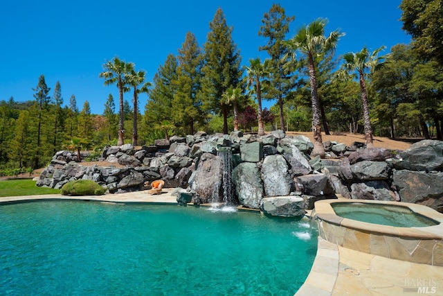 view of swimming pool featuring pool water feature and an in ground hot tub