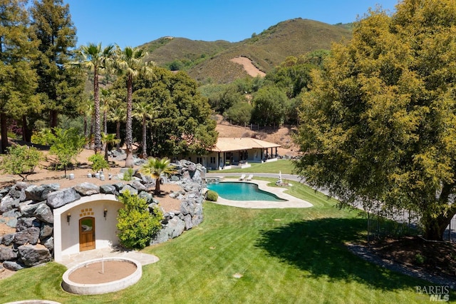 view of swimming pool with a mountain view and a lawn