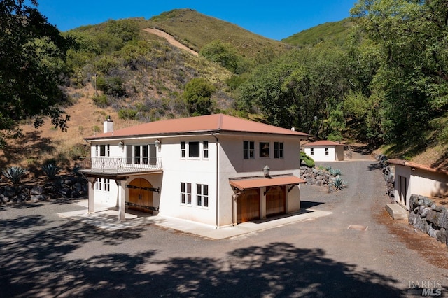 view of front of property with a balcony, a mountain view, and a patio