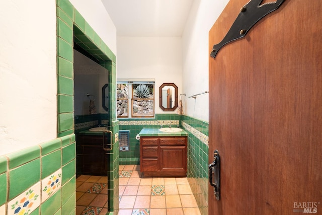 kitchen featuring tile walls, light tile patterned flooring, sink, and tile counters