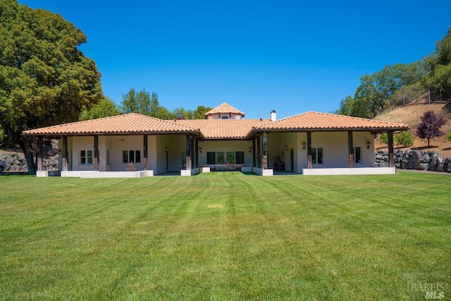 rear view of property featuring a lawn and a patio area