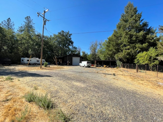 view of yard with an outbuilding, driveway, a detached garage, and fence