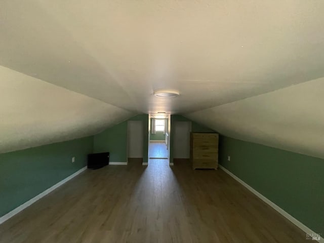 additional living space featuring lofted ceiling, dark wood-type flooring, and baseboards