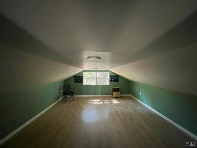 bonus room with vaulted ceiling, wood finished floors, and baseboards