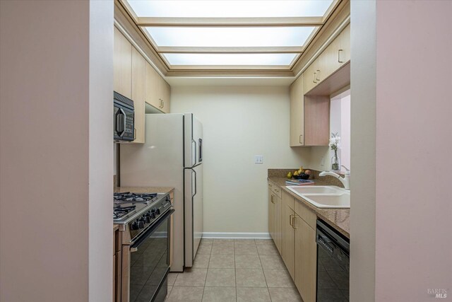 kitchen with black appliances, light brown cabinetry, light tile patterned floors, and sink