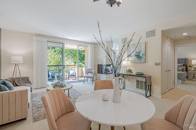 dining space featuring baseboards, visible vents, and light colored carpet