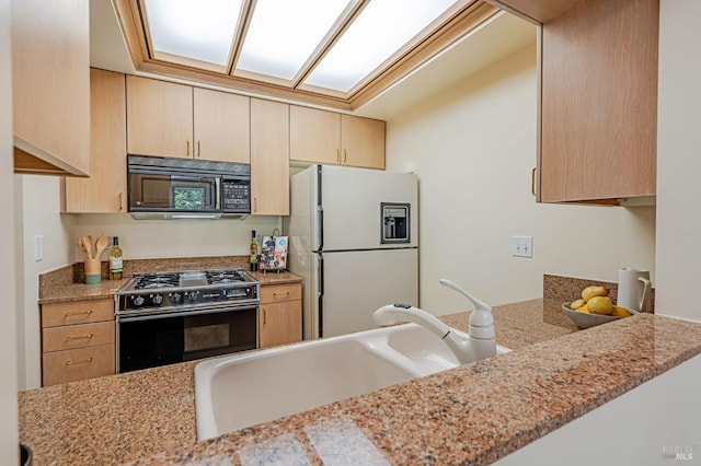 kitchen with light brown cabinets, range with gas cooktop, a sink, white refrigerator with ice dispenser, and black microwave