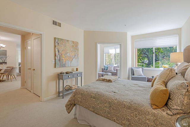 bedroom featuring baseboards, visible vents, a notable chandelier, and light colored carpet
